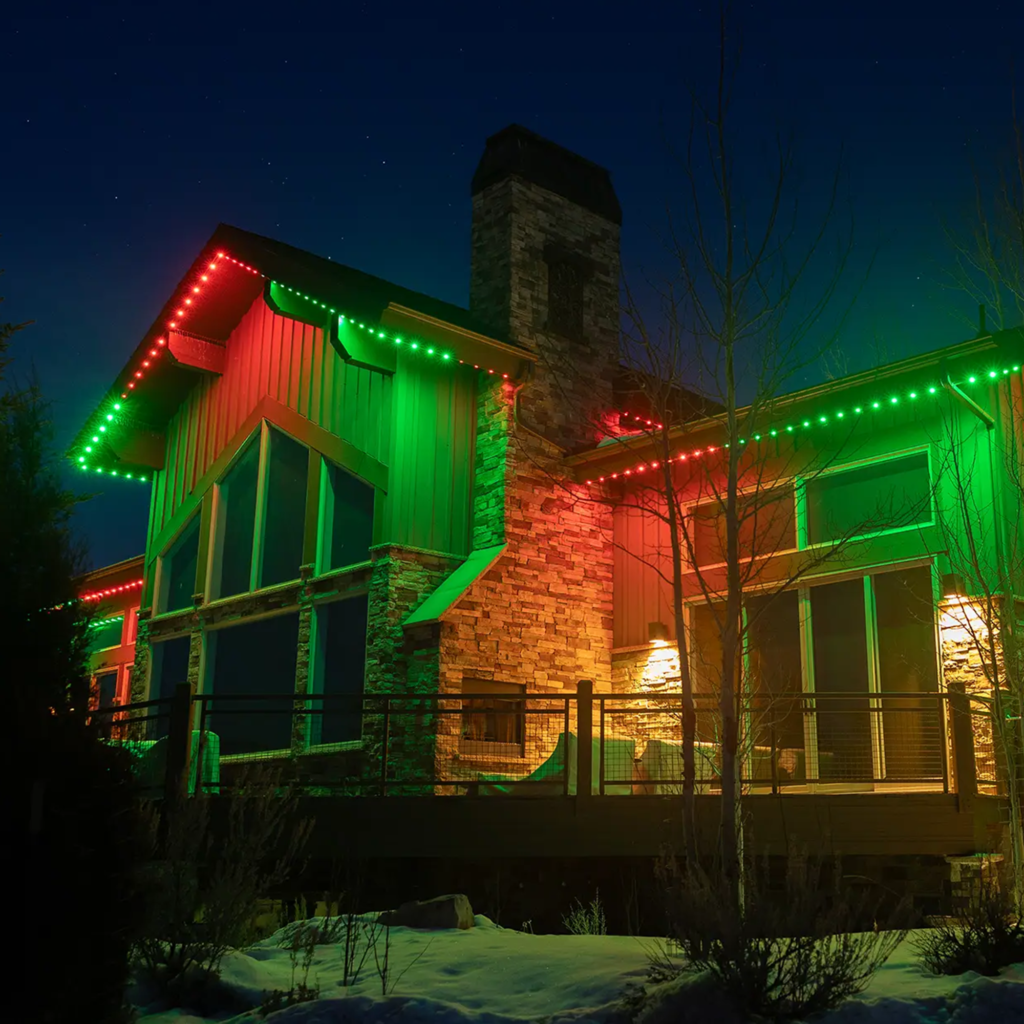 Fotis Infinity Lights lit up green and red on a house in the snow at night.